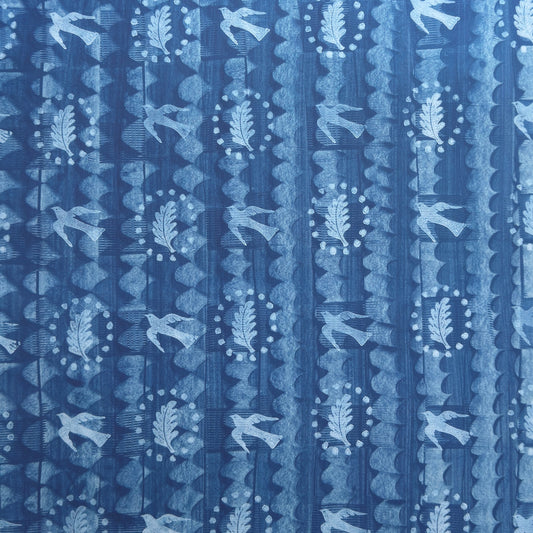 a sheet of wrapping paper with a relief printed oak leaf and bird in white on a blue paste paper backdrop