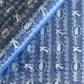 a sheet of wrapping paper with a relief printed oak leaf and bird in white on a blue paste paper backdrop