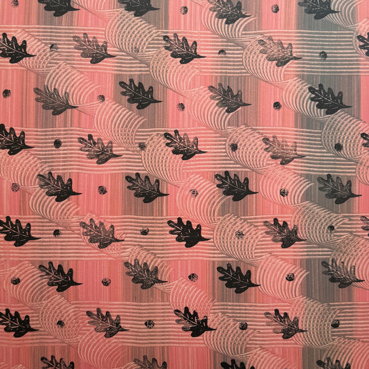  a sheet of wrapping paper with a relief printed black oak leaf on a coral pink paste paper backdrop