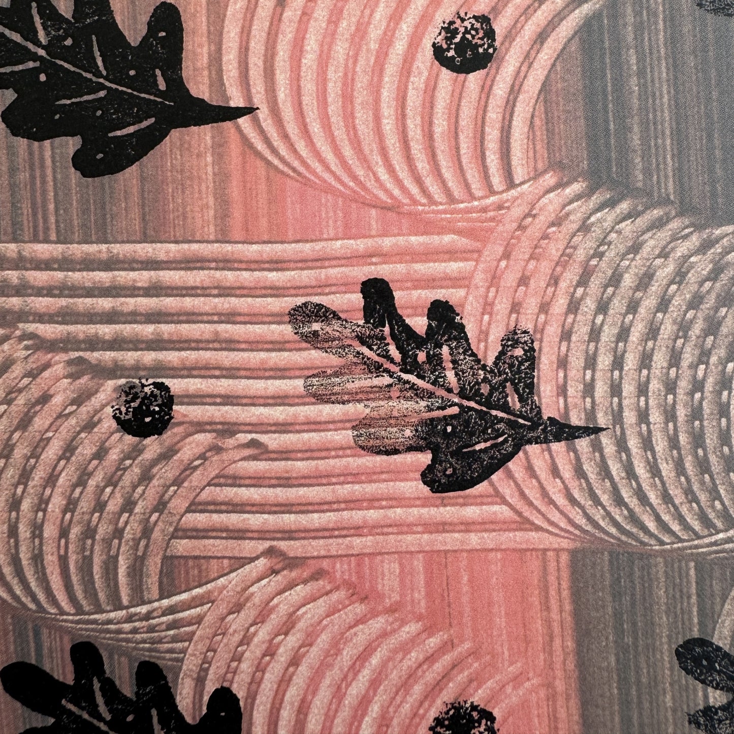  a sheet of wrapping paper with a relief printed black oak leaf on a coral pink paste paper backdrop