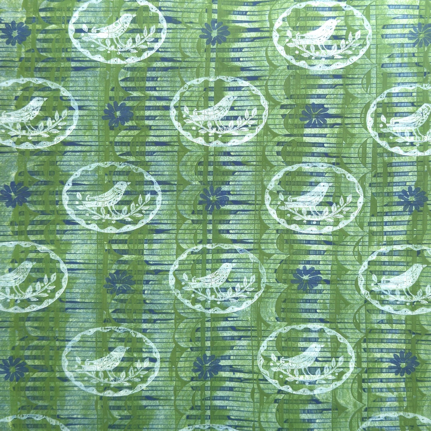 a sheet of wrapping paper from the Danby Press with a  backdrop of green paste paper design and circular stamped white bird motifs