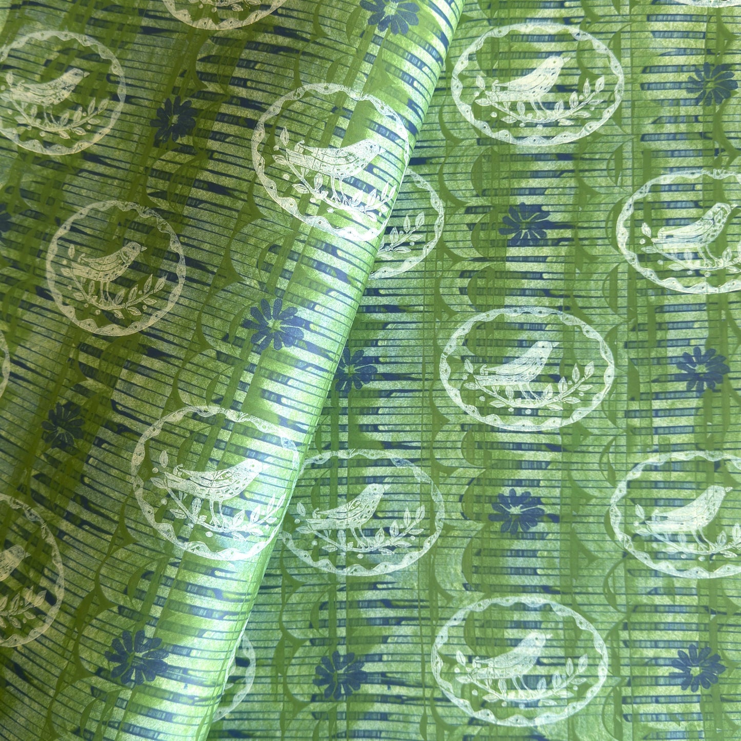 a sheet of wrapping paper from the Danby Press with a  backdrop of green paste paper design and circular stamped white bird motifs