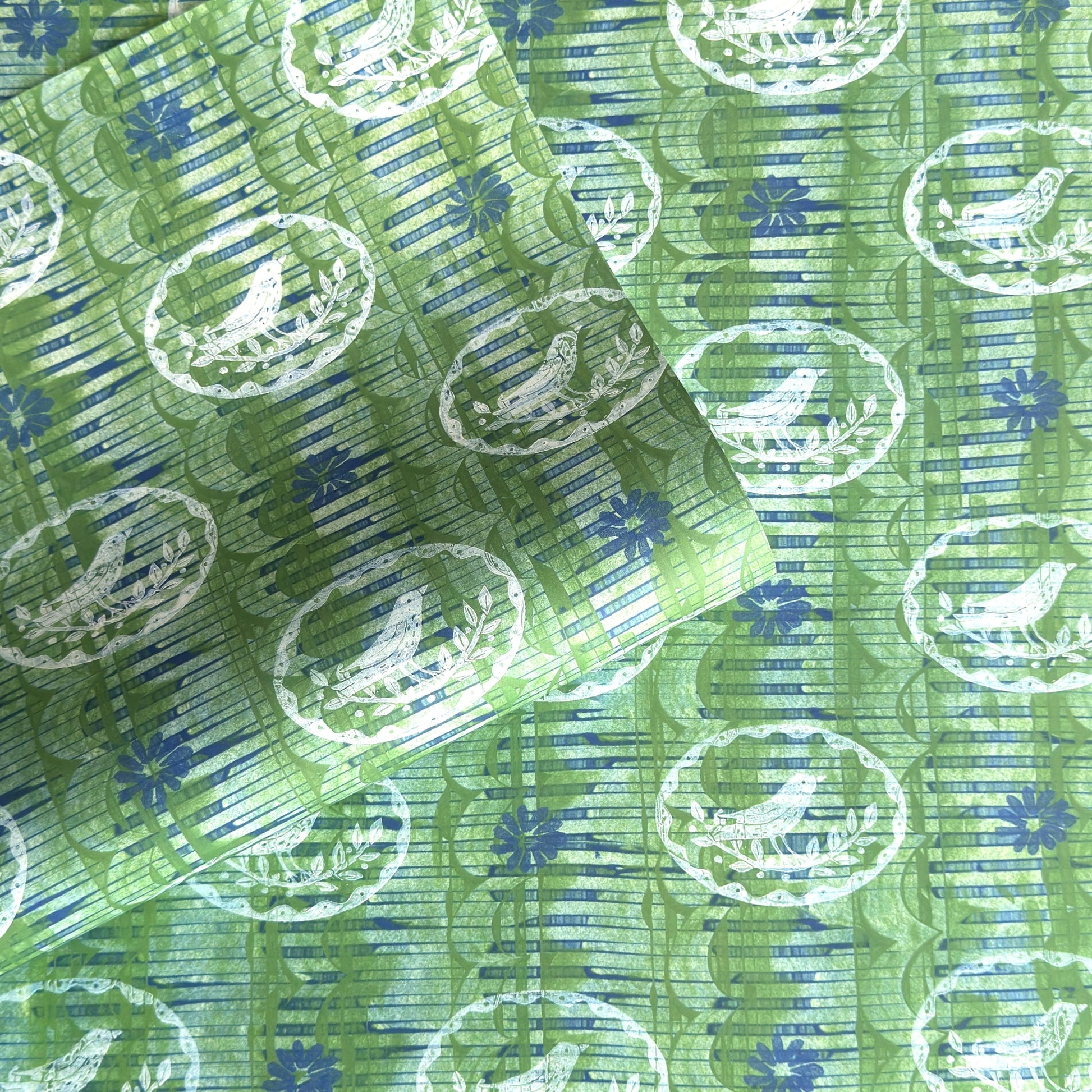 a sheet of wrapping paper from the Danby Press with a  backdrop of green paste paper design and circular stamped white bird motifs