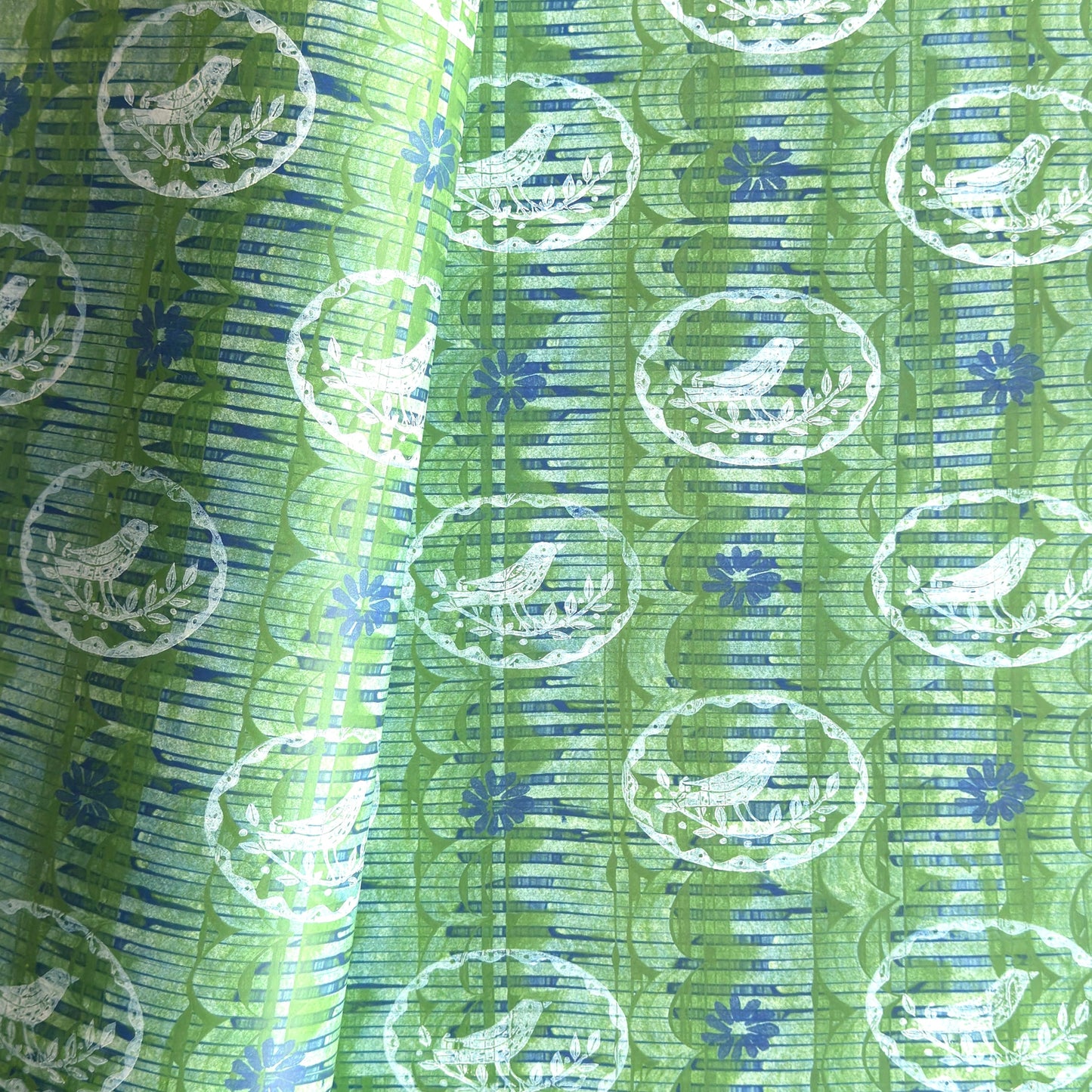 a sheet of wrapping paper from the Danby Press with a  backdrop of green paste paper design and circular stamped white bird motifs