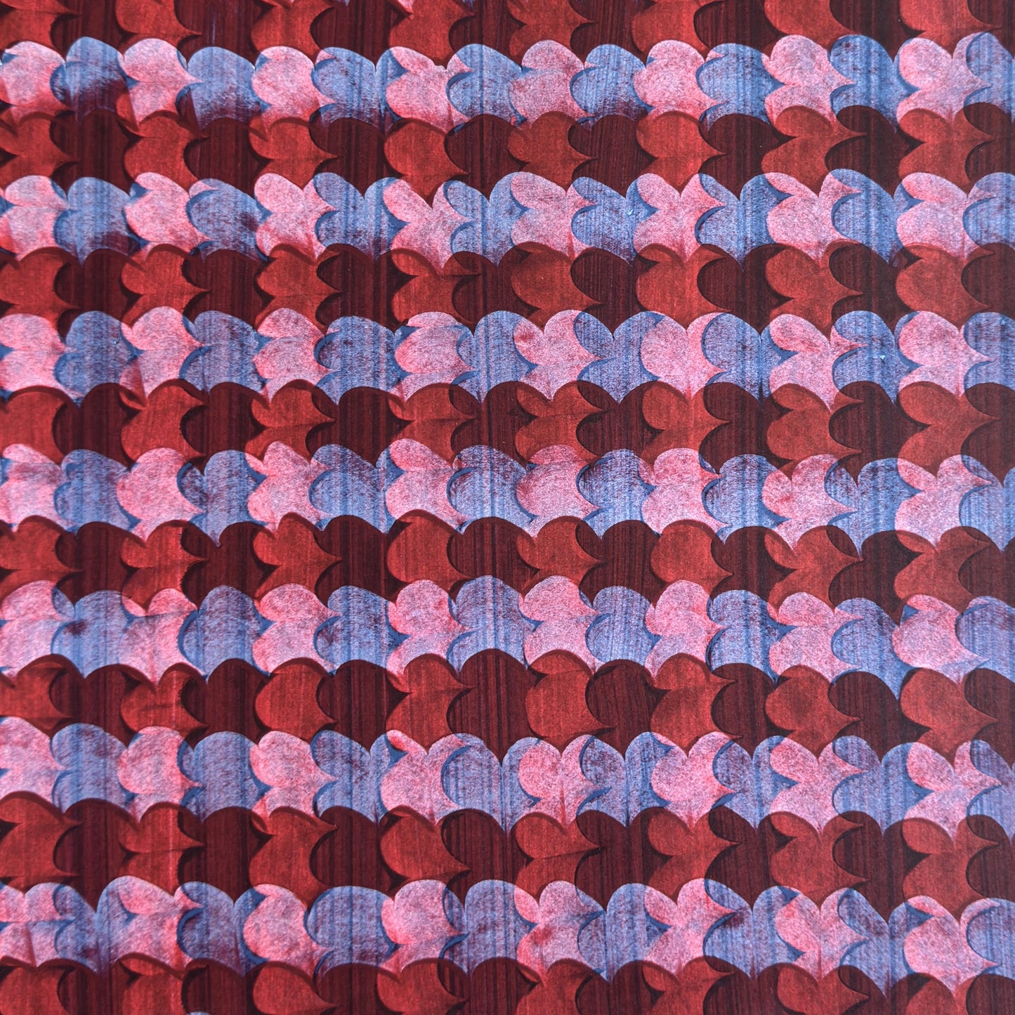 a sheet of wrapping paper with an abstract block print in dark red, pink and blue