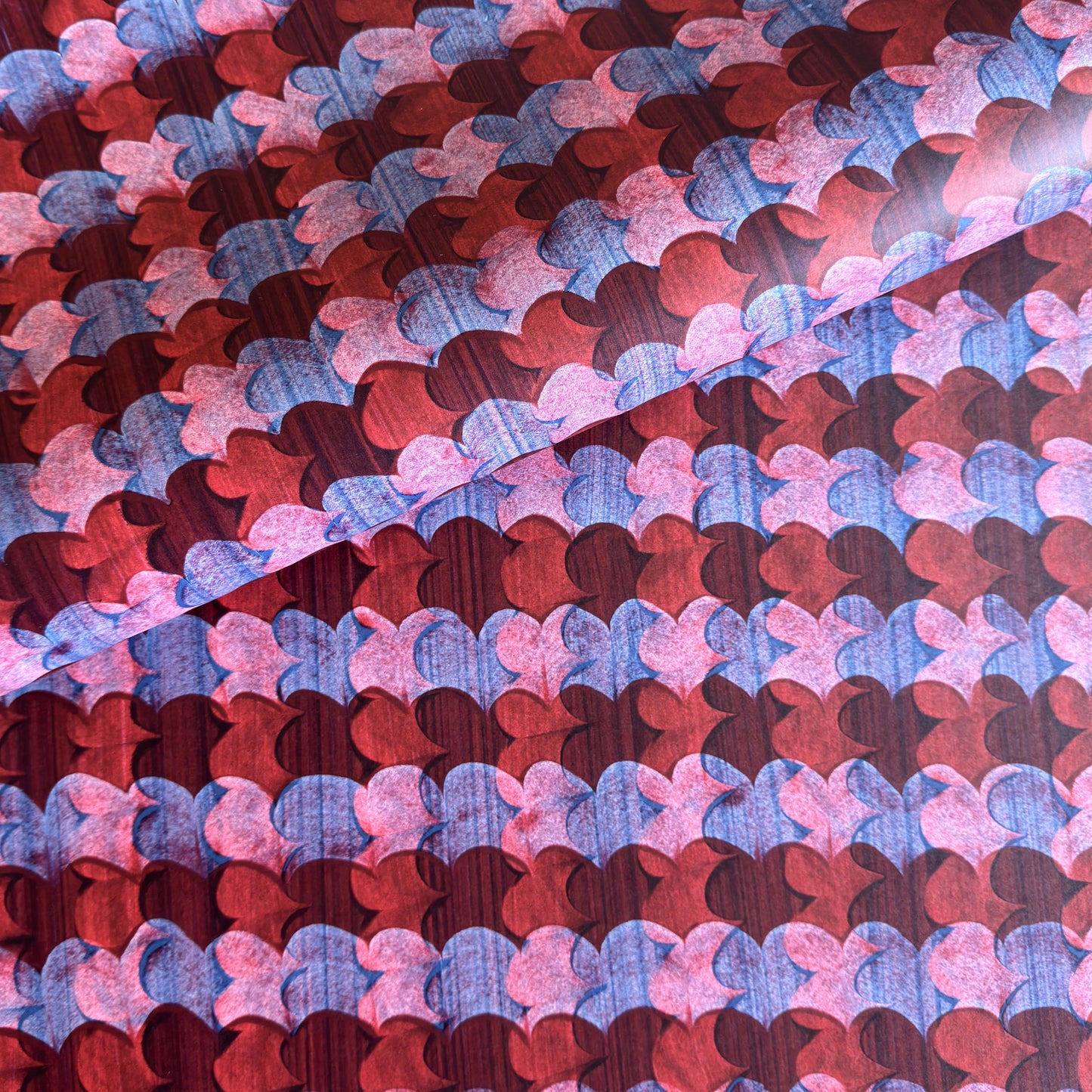a sheet of wrapping paper with an abstract block print in dark red, pink and blue
