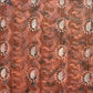 a sheet of wrapping paper with a relief printed oak leaf in white on a rust brown paste paper backdrop