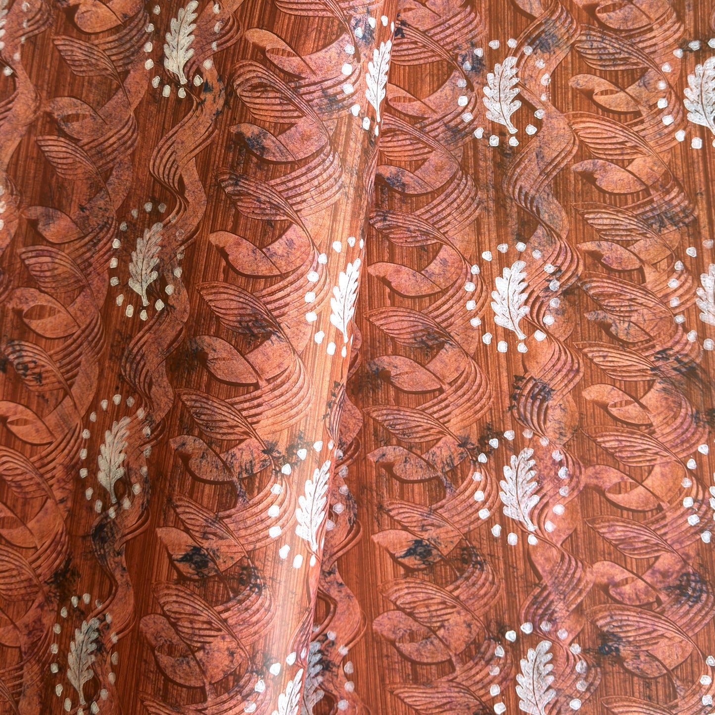  a sheet of wrapping paper with a relief printed oak leaf in white on a rust brown paste paper backdrop