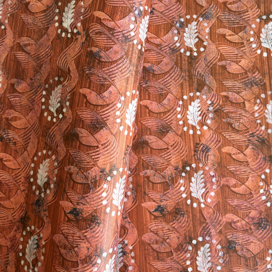  a sheet of wrapping paper with a relief printed oak leaf in white on a rust brown paste paper backdrop