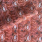 a sheet of wrapping paper with a relief printed oak leaf in white on a rust brown paste paper backdrop