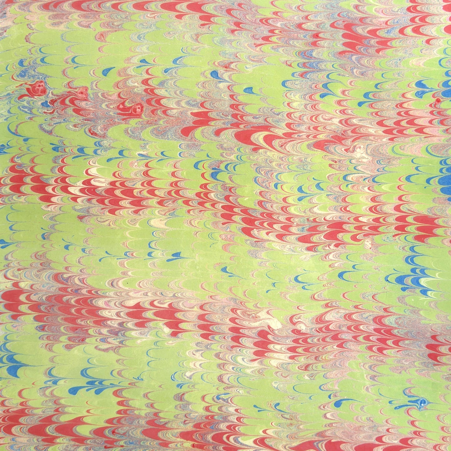 a sheet of wrapping paper with a marbled design in lime green, red and blue