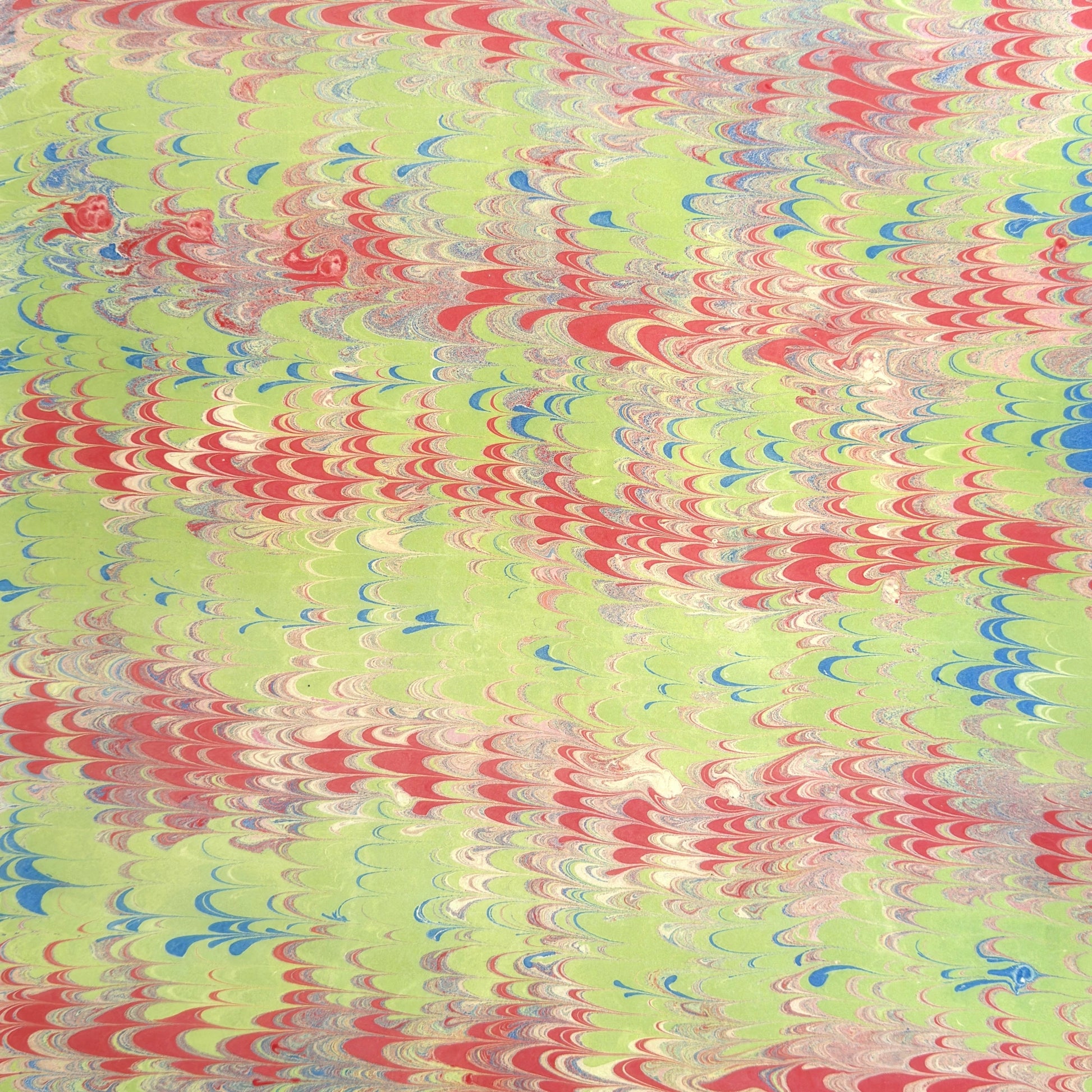 a sheet of wrapping paper with a marbled design in lime green, red and blue
