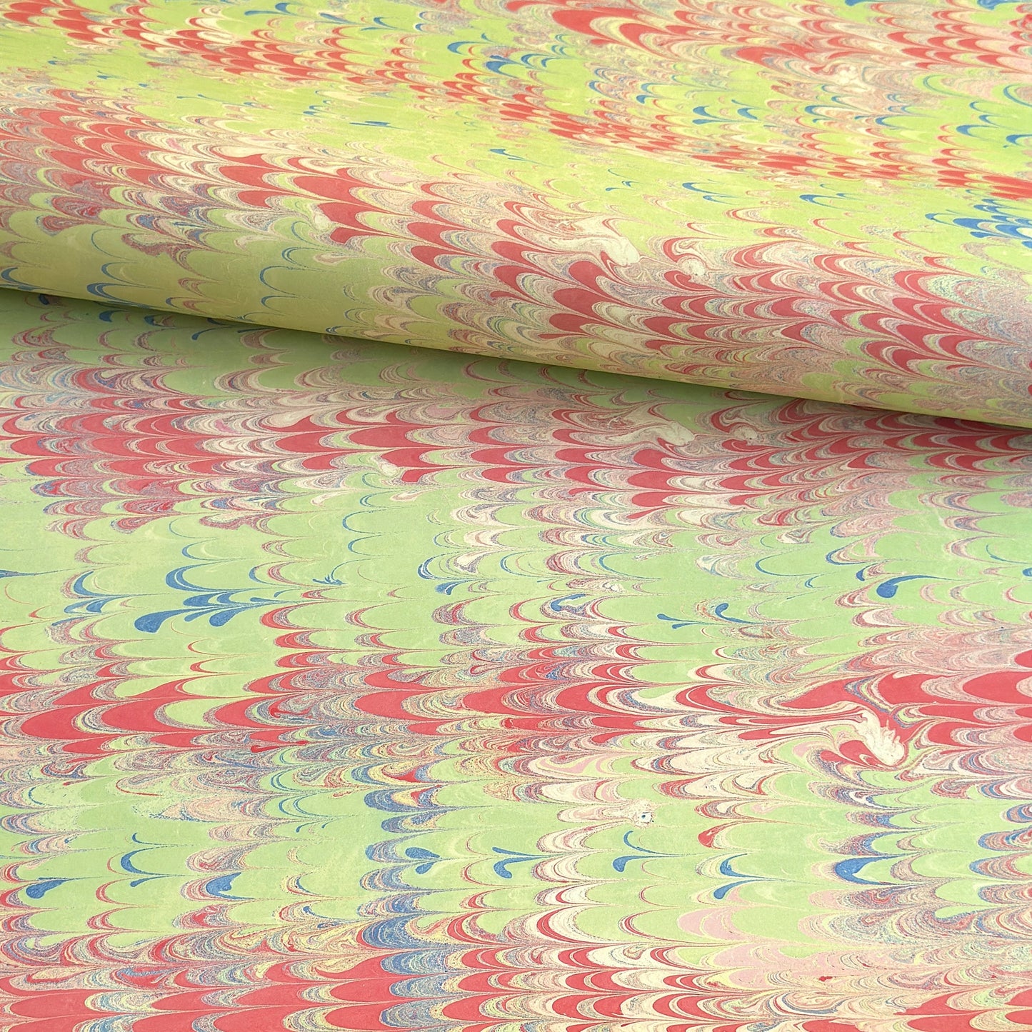 a sheet of wrapping paper with a marbled design in lime green, red and blue