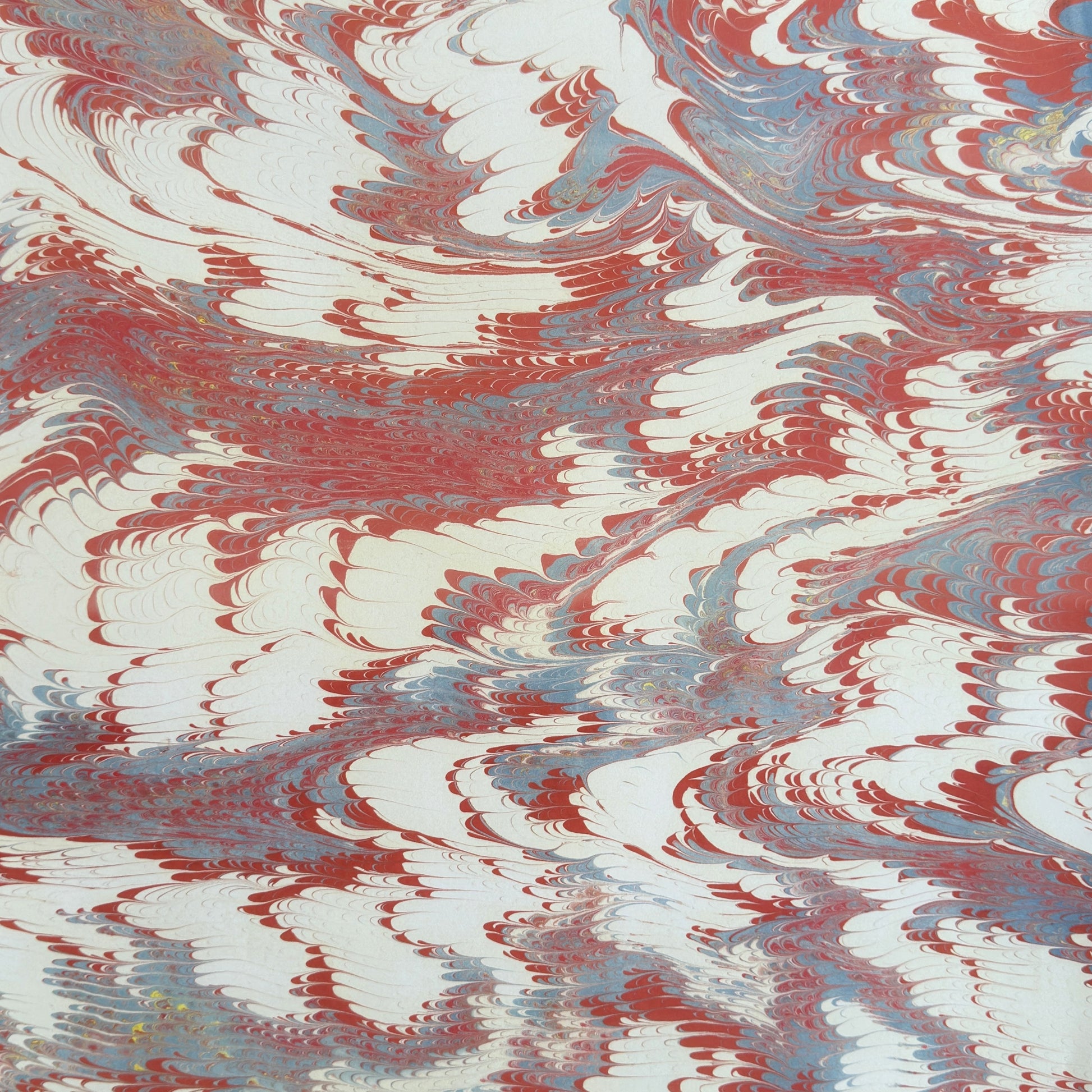 a sheet of wrapping paper with a marbled design in red, blue and white