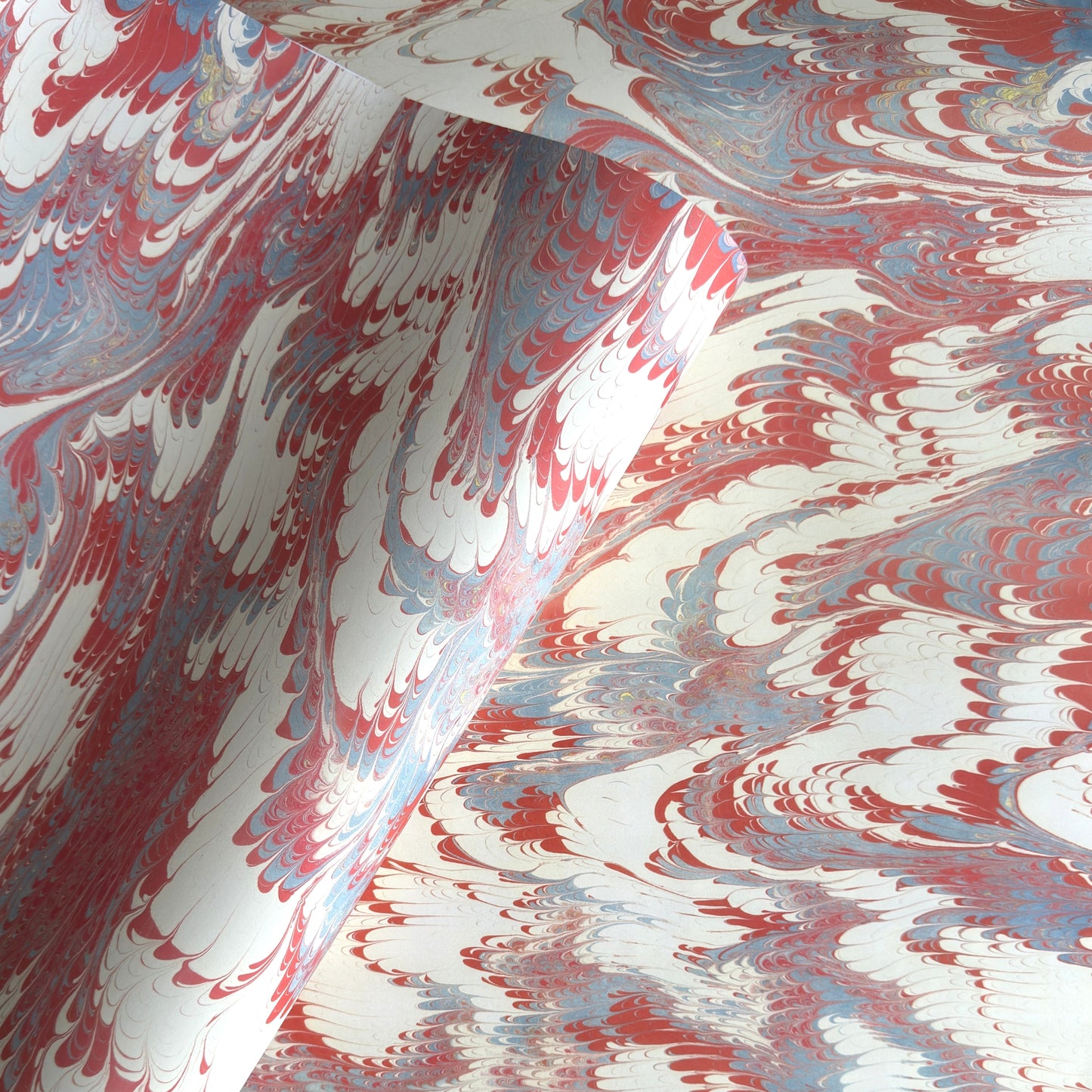 a sheet of wrapping paper with a marbled design in red, blue and white
