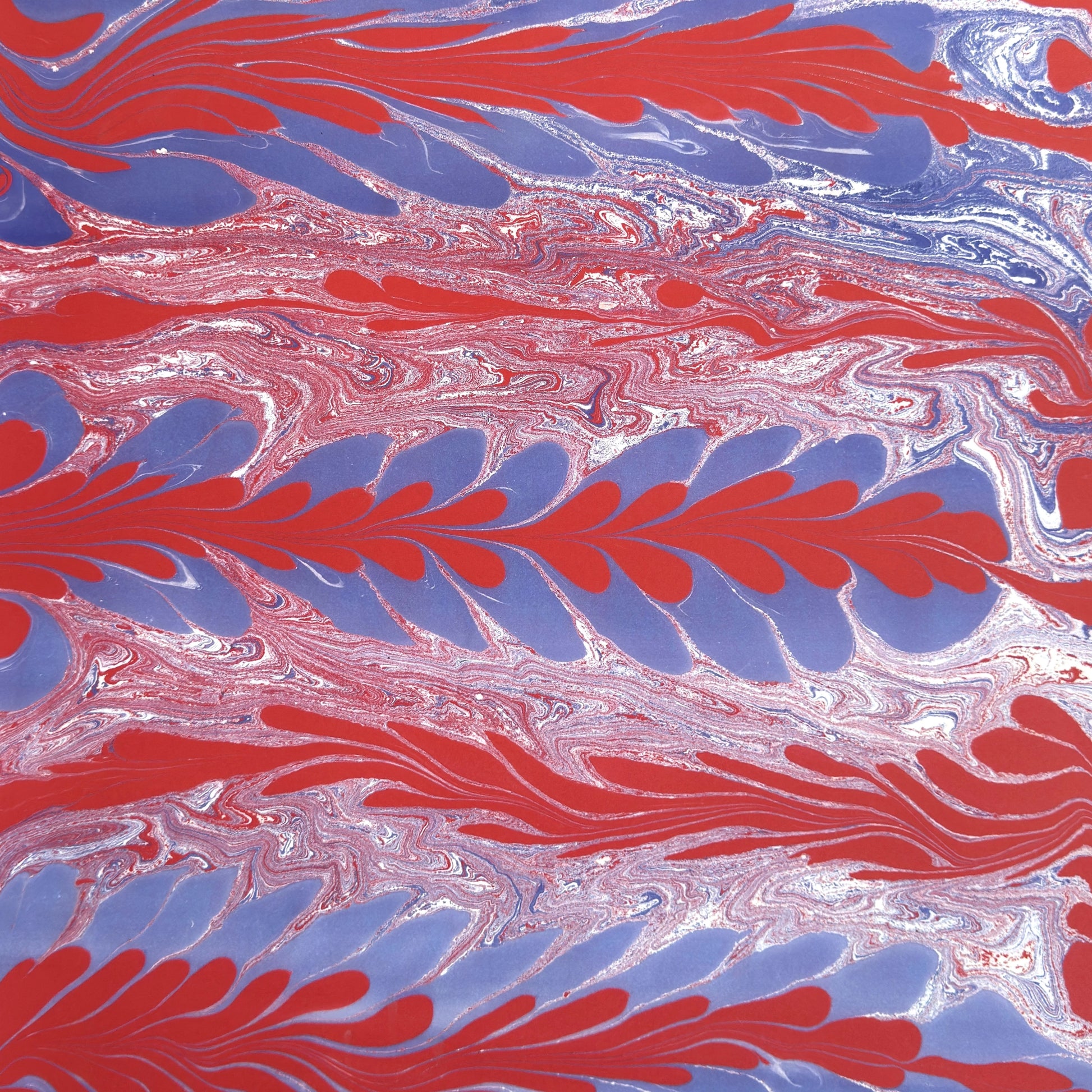 a sheet of wrapping paper with a marbled design in red, purple and white