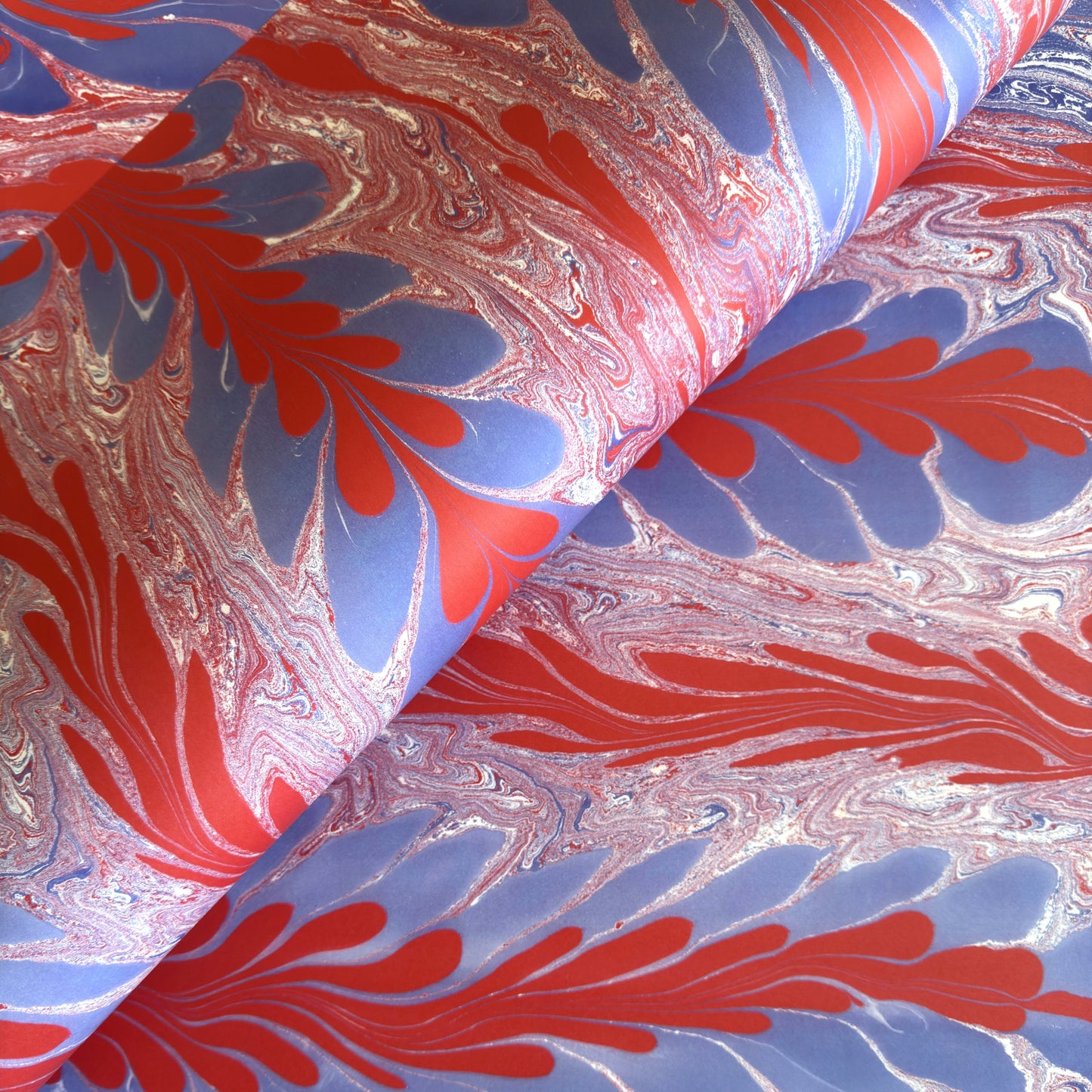 a sheet of wrapping paper with a marbled design in red, purple and white