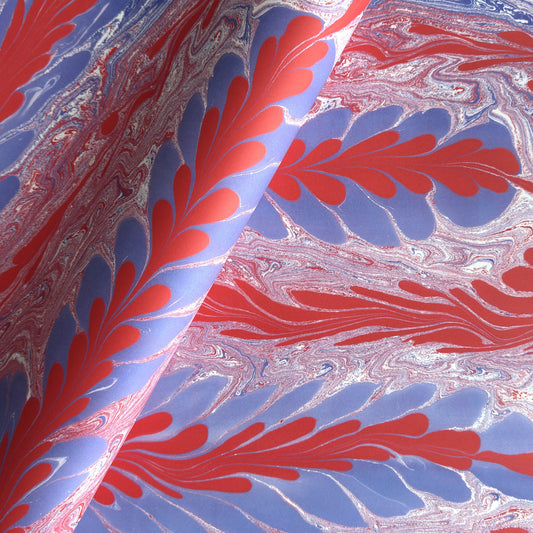 a sheet of wrapping paper with a marbled design in red, purple and white