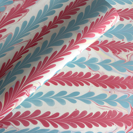 a sheet of wrapping paper with a marbled design in pink, blue and white