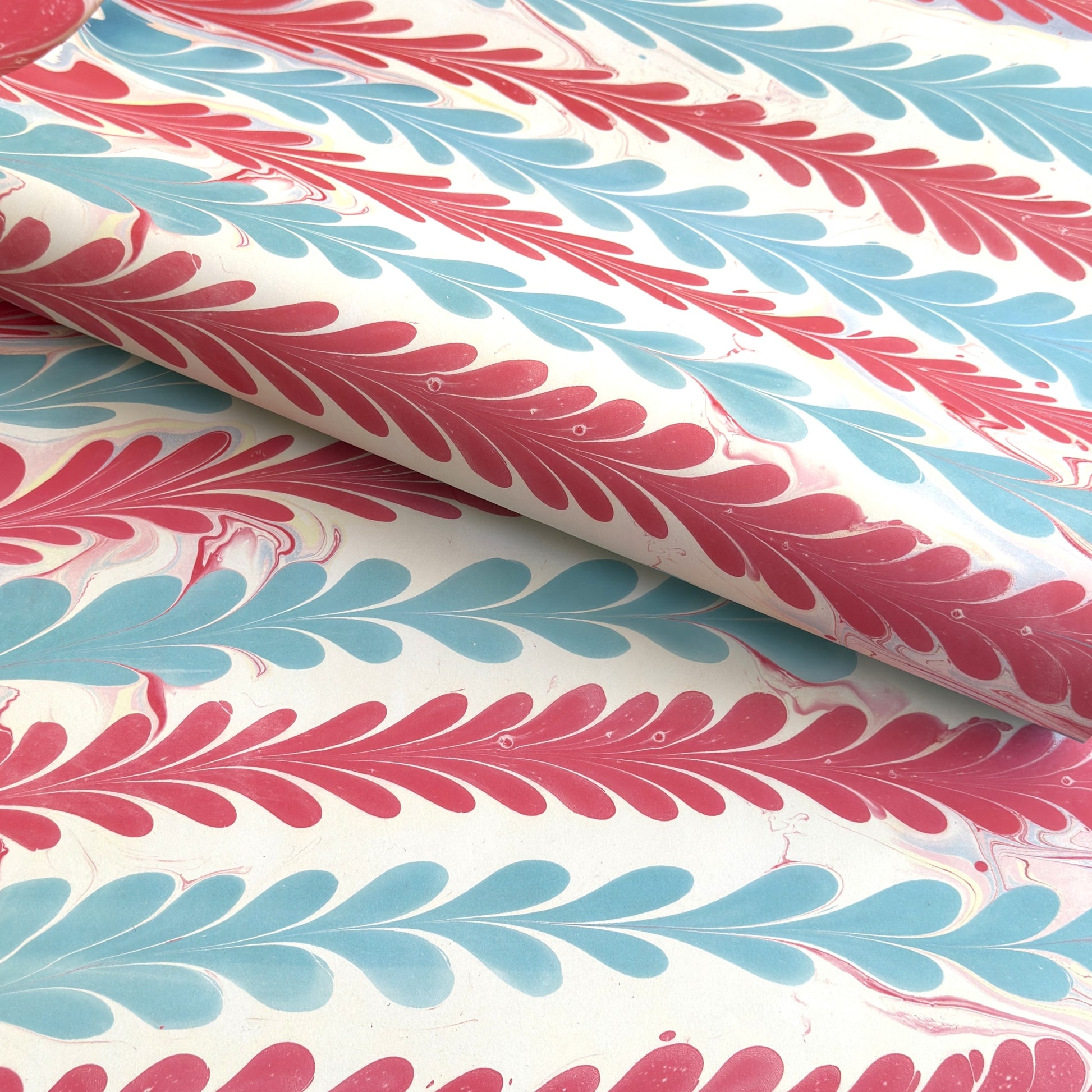 a sheet of wrapping paper with a marbled design in pink, blue and white