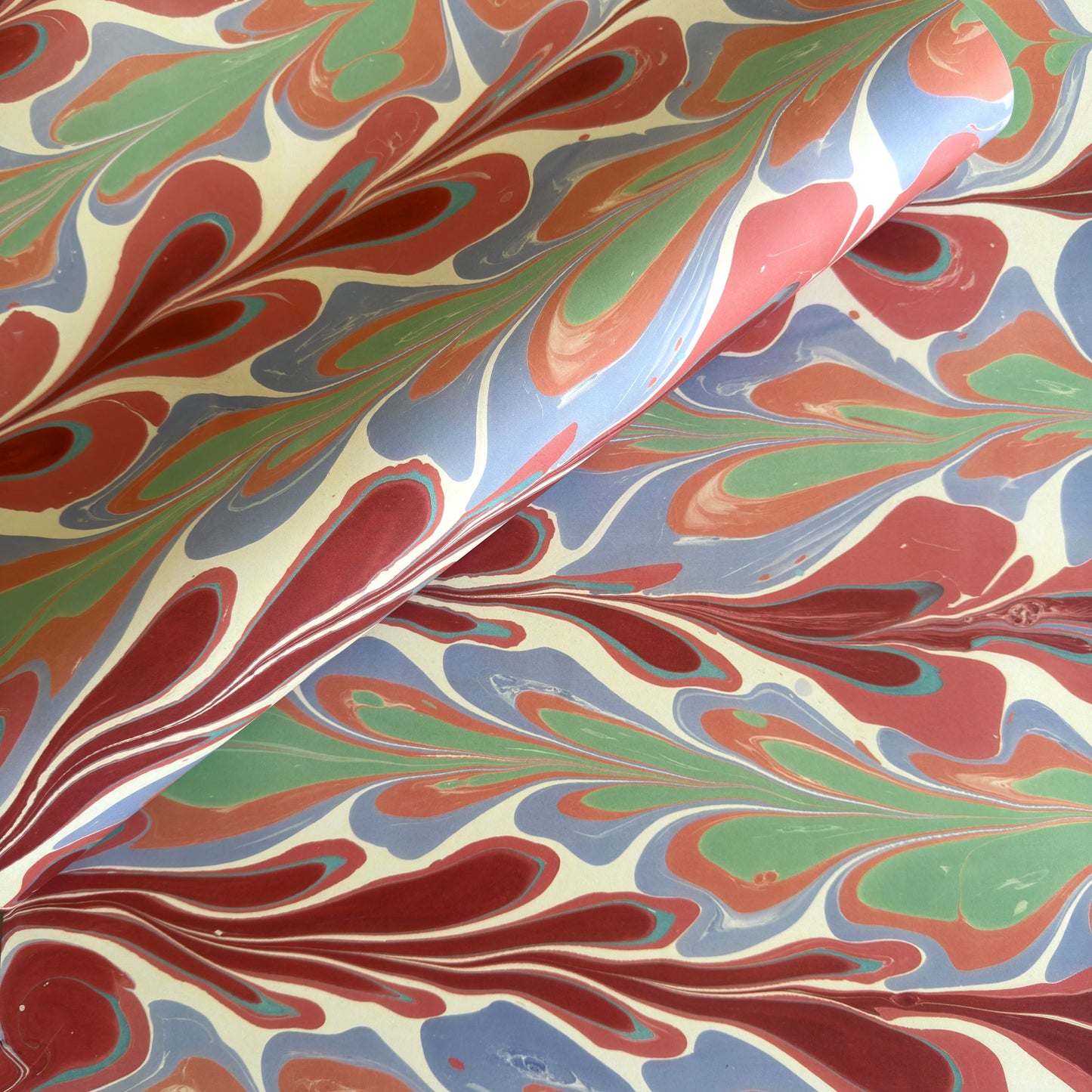 a sheet of wrapping paper with a marbled design in pink, blue, green and red