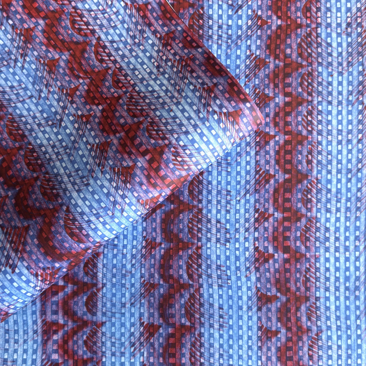 a sheet of wrapping paper with a paste paper style design in blue and dark red