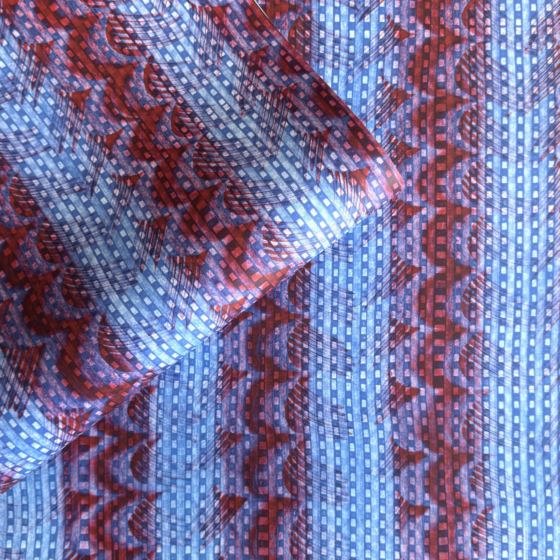 a sheet of wrapping paper with a paste paper style design in blue and dark red