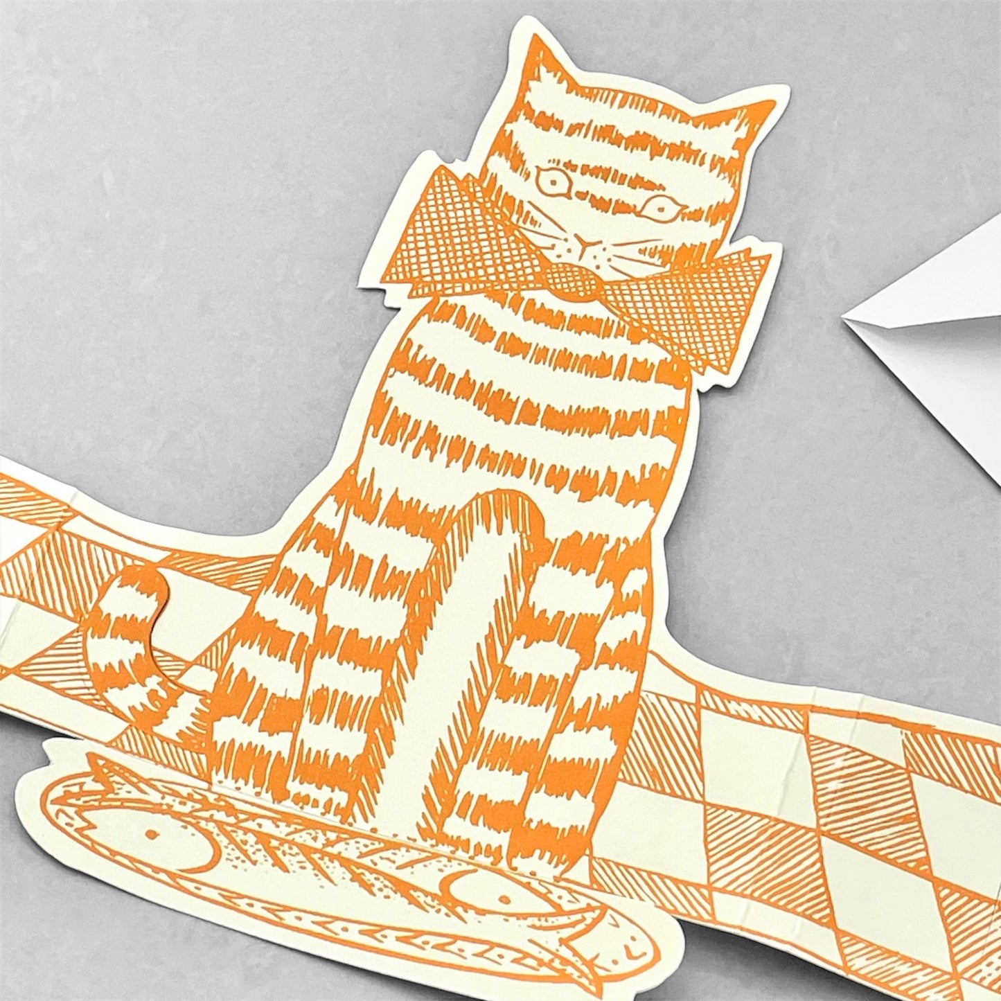 A cut-out and stand up greetings card of an orange cat with a plate of mackerel, by Elizabeth Harbour