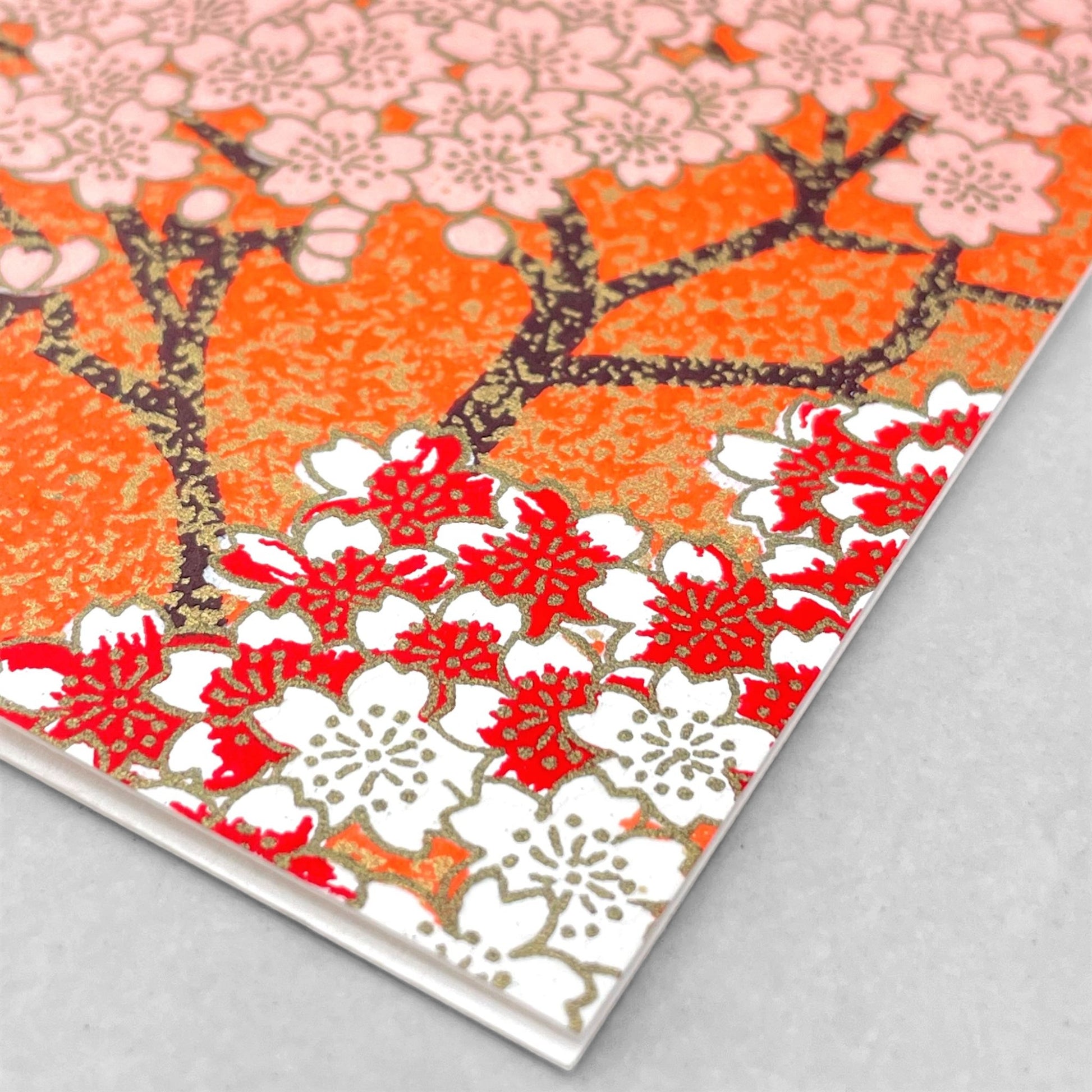 japanese silk-screen printed greetings card with a pattern of peach, white and red blossom branches on an orange backdrop by Esmie