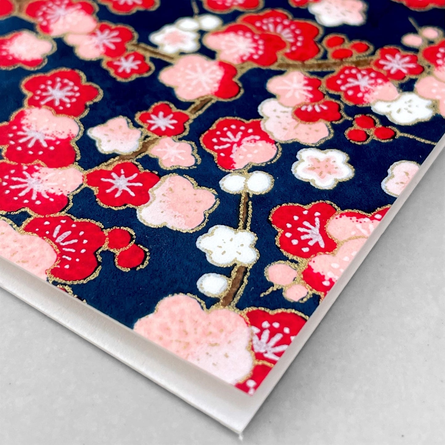 japanese silk-screen printed greetings card with a repeat pattern of pink and red blossom branches on a dark blue backdrop by Esmie
