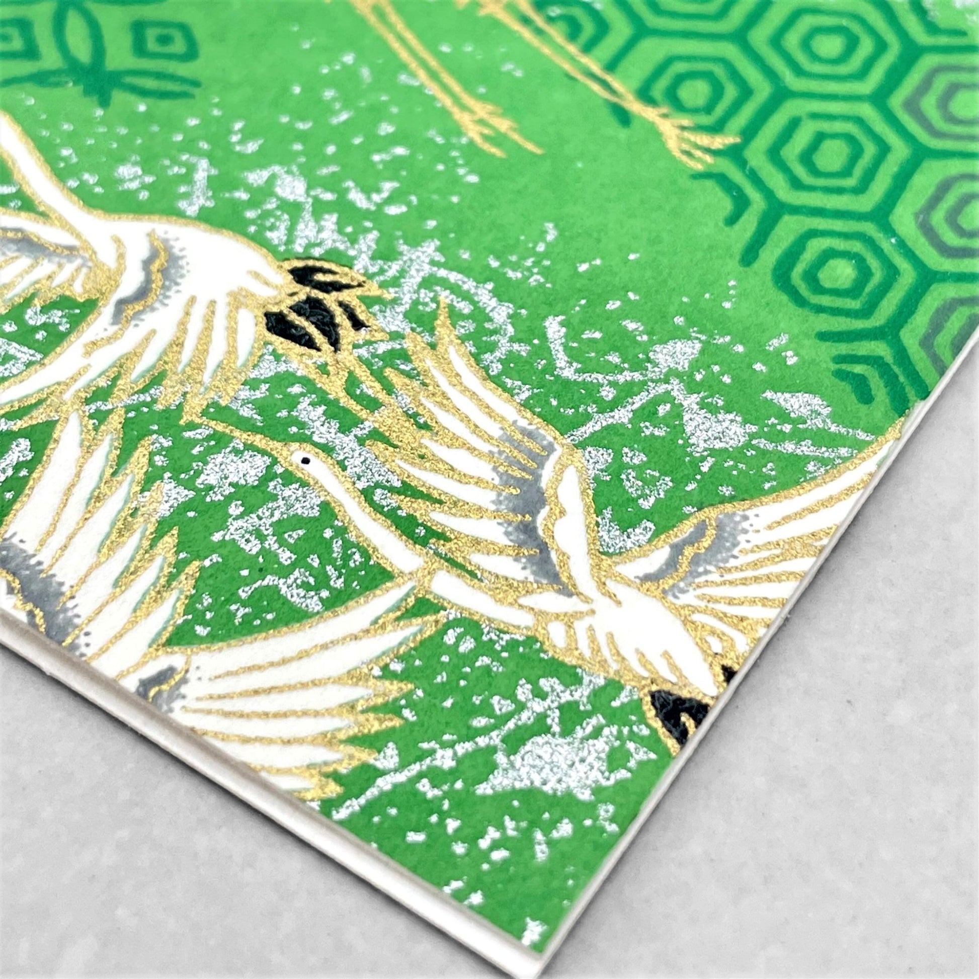 japanese silk-screen printed greetings card with a pattern of white cranes in flight on a green backdrop of japanese motifs by Esmie