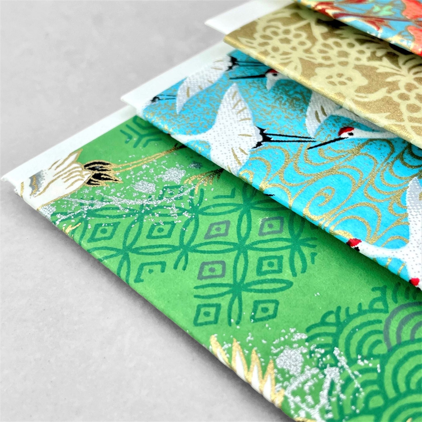 japanese silk-screen printed greetings card with a pattern of white cranes in flight on a green backdrop of japanese motifs by Esmie
