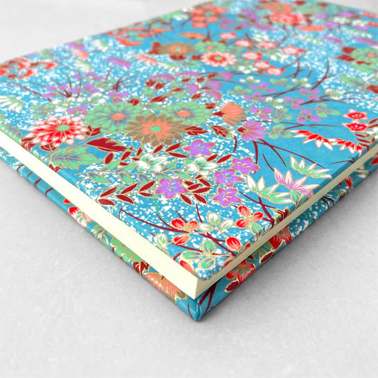 hardback A5 plain notebook with cover made of japanese silkscreen chiyogami paper. Multicolour floral bouquet pattern on teal background by Esmie