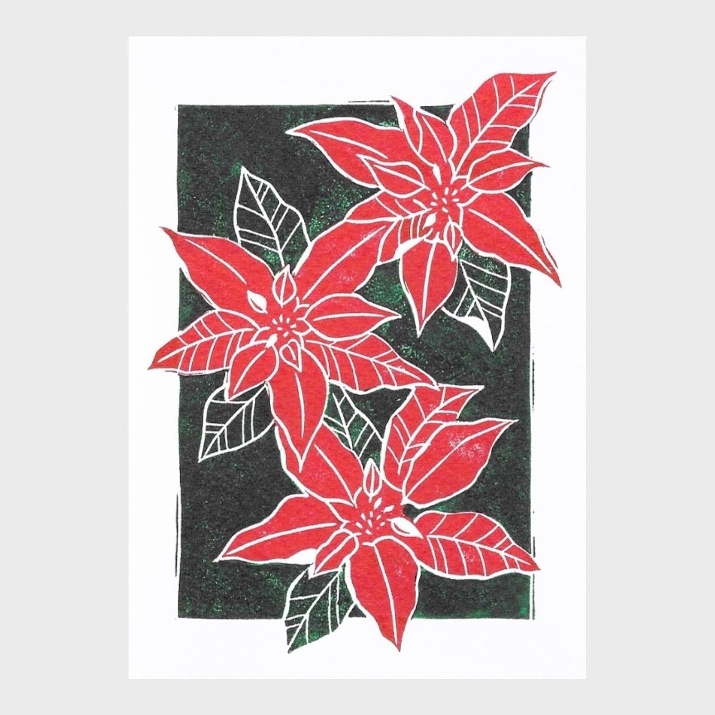 Greeting card with a linocut print of a poinsetta in red and green