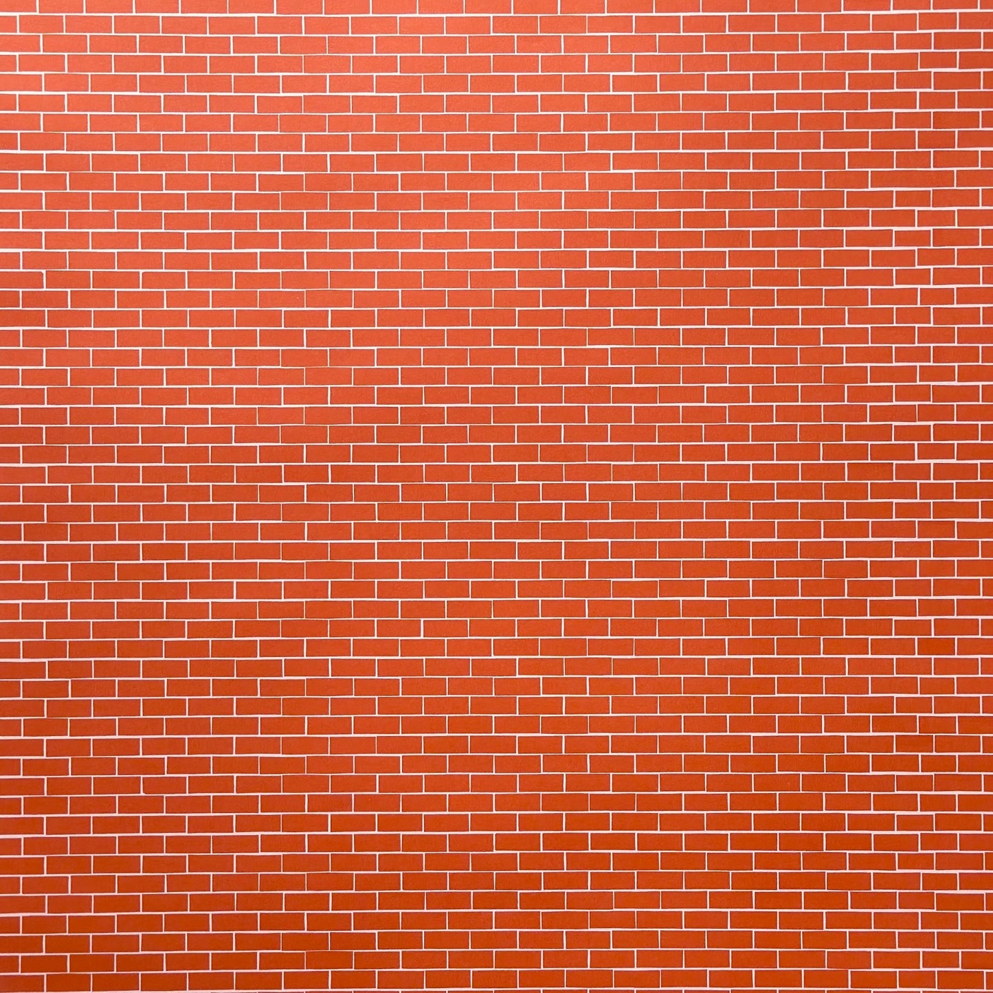 a sheet of gift wrap with a small brick design in rich red and pink