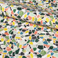 Colorful terrazzo pattern on a pale pink background. A sheet of wrapping paper
