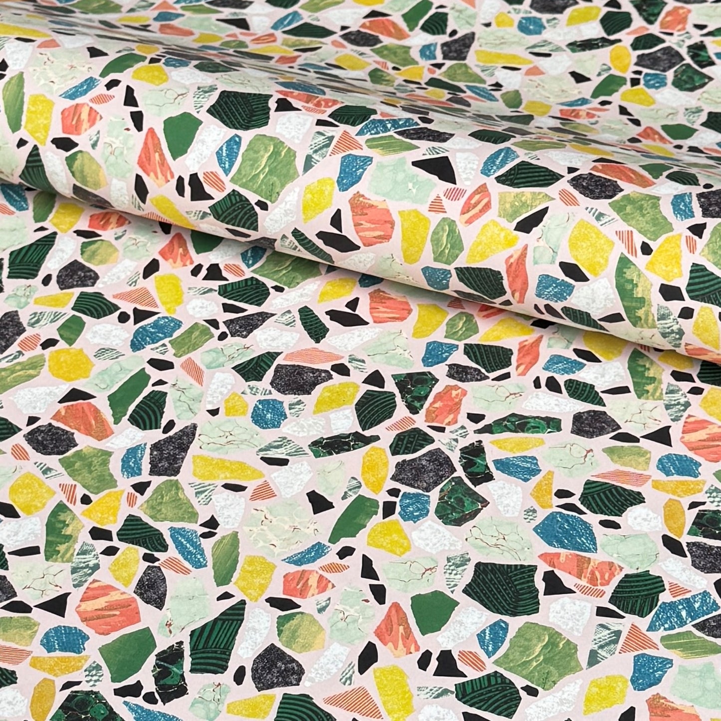 Colorful terrazzo pattern on a pale pink background. A sheet of wrapping paper