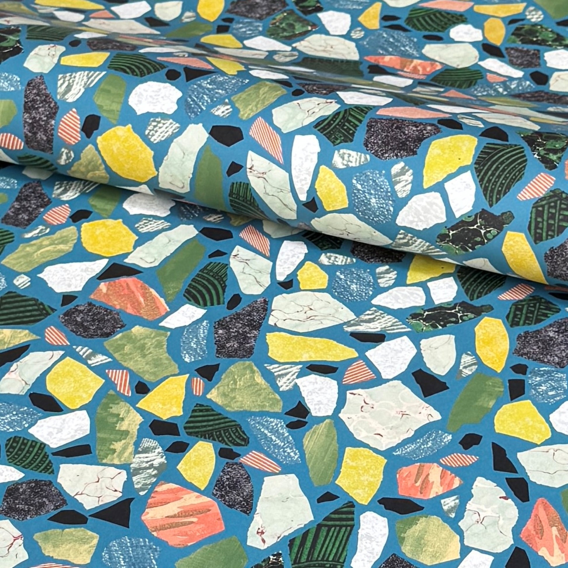 a sheet of wrapping paper with a teal blue background and terrazzo pattern