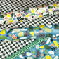 Colorful terrazzo pattern on a pale pink background. Rolled sheet of wrapping paper on a chequerboard backdrop