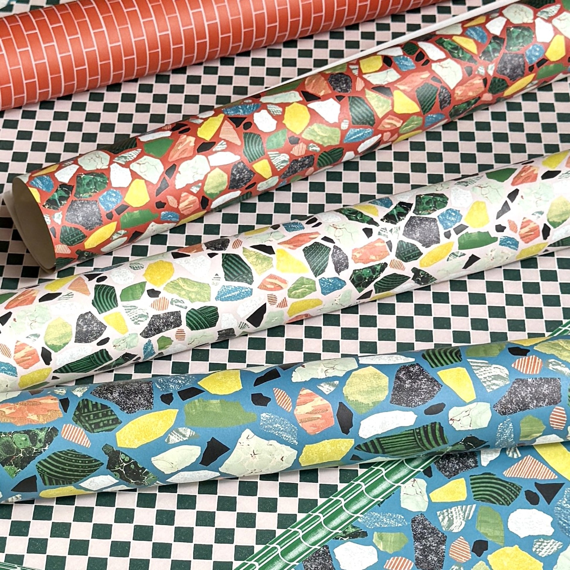 Rolls of colorful patterned paper on a checkered surface