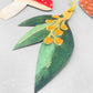 A set of five different festive plant gift tags in red, green and yellow with colourful sttring, by Hadley Paper Goods, pictured a leaf