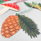 A set of five different festive plant gift tags in red, green and yellow with colourful sttring, by Hadley Paper Goods, pictured a pine cone