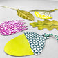 A set of five different plant shaped gift tags in colours of green, yellow and purple, with colourful string by Hadley Paper Goods, pictured an acorn