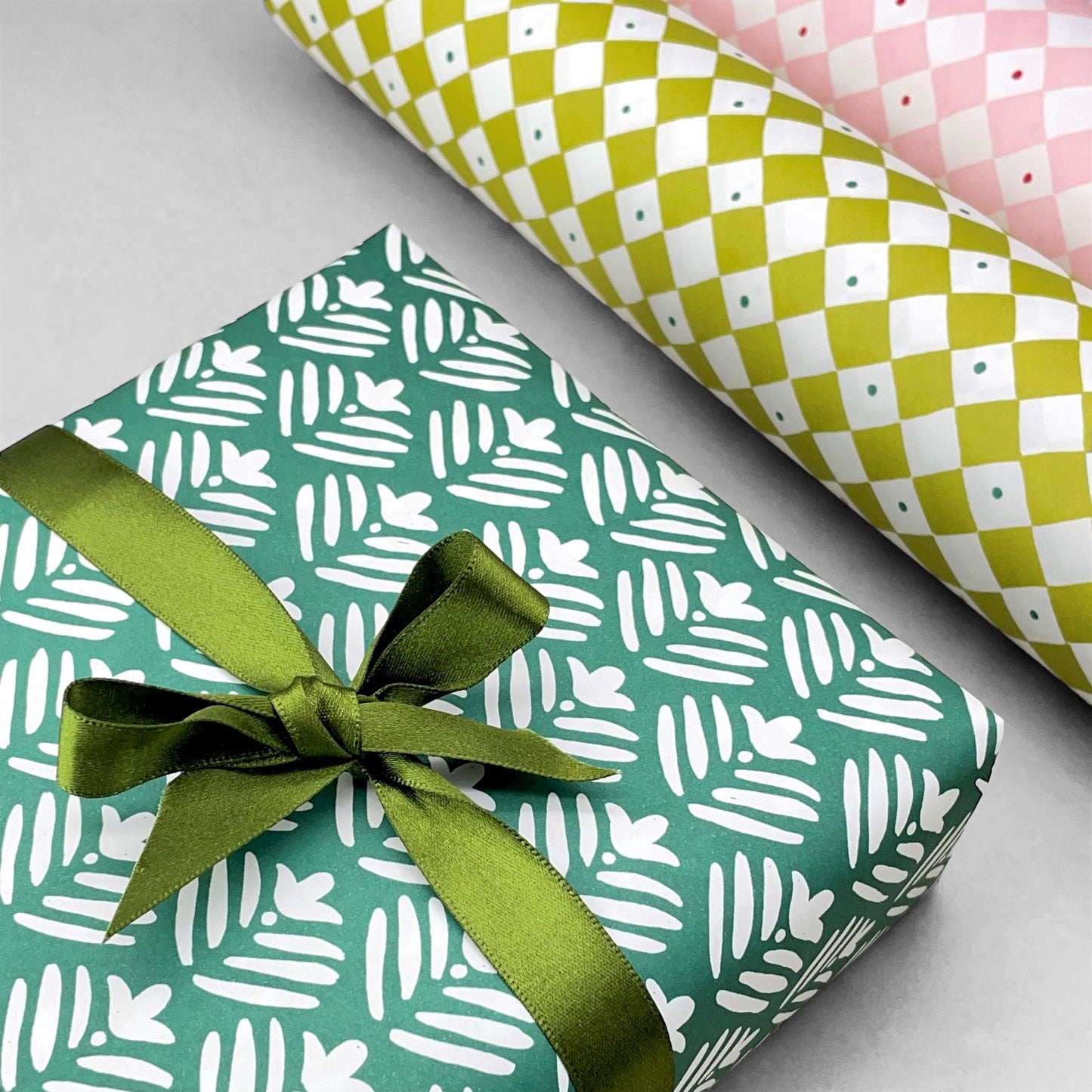 wrapping paper with emerald green backdrop and a white flower repeat pattern by Heather Evelyn