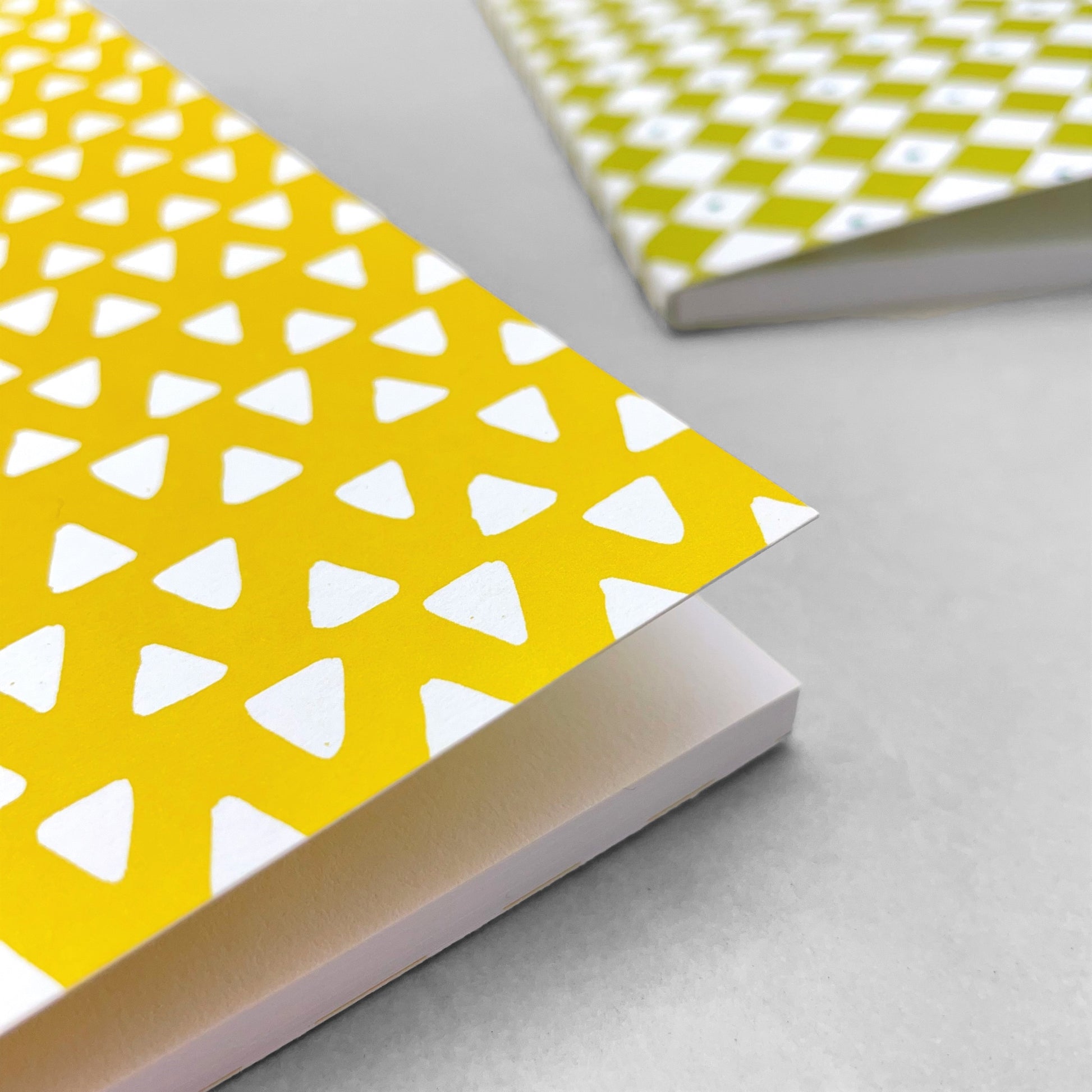 A5 notebook with bright yellow cover and repeat pattern of white triangles by Heather Evelyn