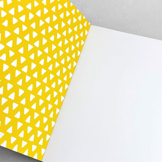 A5 notebook with bright yellow cover and repeat pattern of white triangles by Heather Evelyn