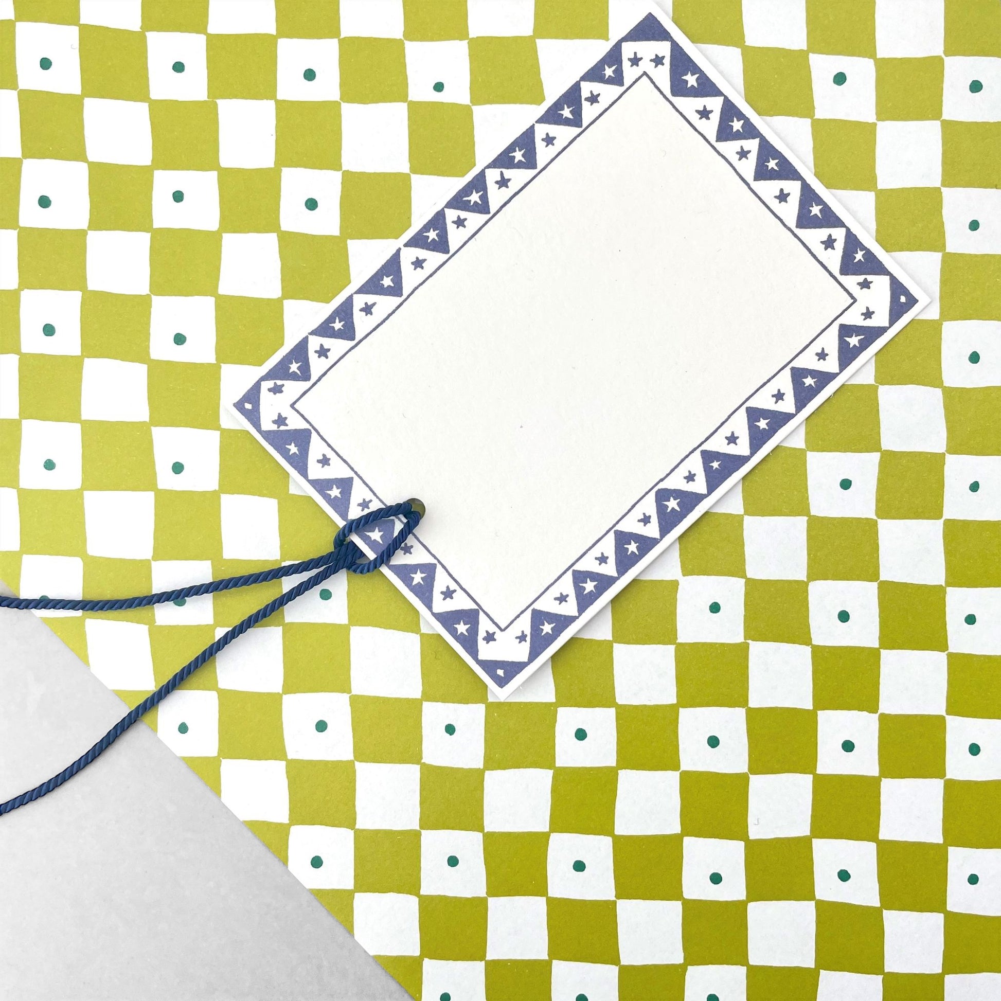 White rectangular gift tag with dark blue star pattern border and blue cord by Heather Evelyn