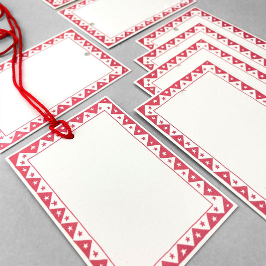 White rectangular gift tag with dark red star pattern border and red cord by Heather Evelyn