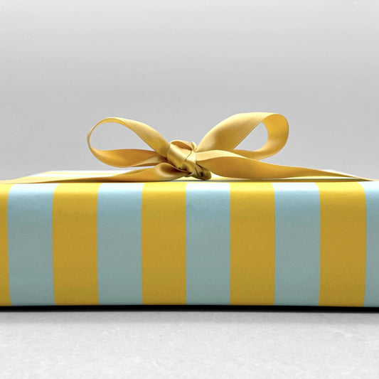 wide classic stripe wrapping paper in blue & yellow by Heather Evelyn. Shown wrapped with gold ribbon bow