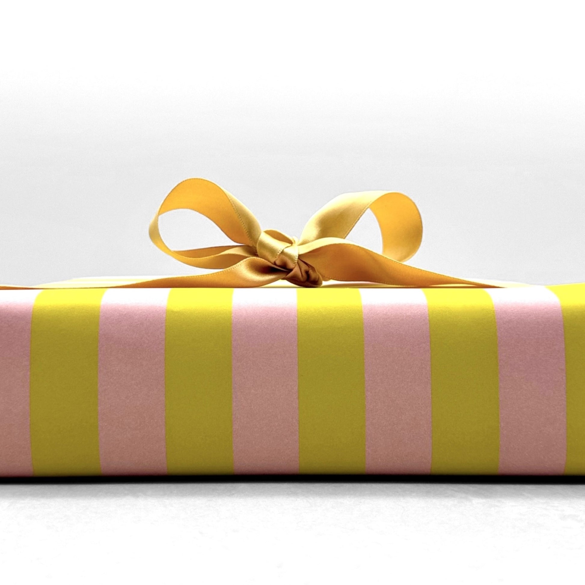 wide classic stripe wrapping paper in lime green and dusty pink by Heather Evelyn, pictured wrapped with gold ribbon